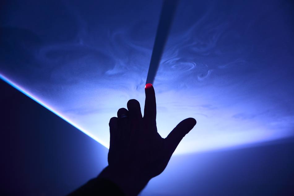 A guest reaching into a beam of light in the haze above the Tabula Rasa table