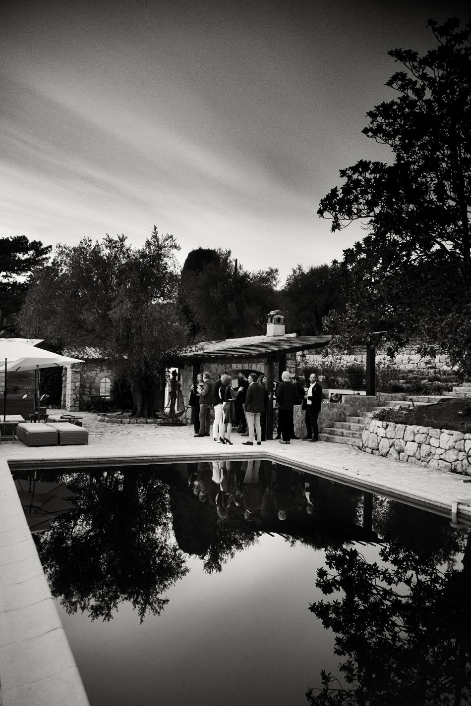 Guests gathering for drinks at dusk beside a pool at the first Tabula Rasa dinner