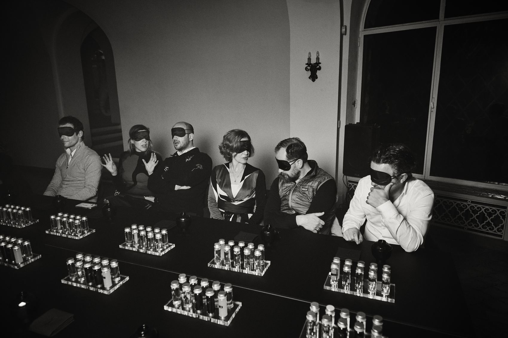 Guests seated at the long table, still blindfolded, before the light and sound composition begins
