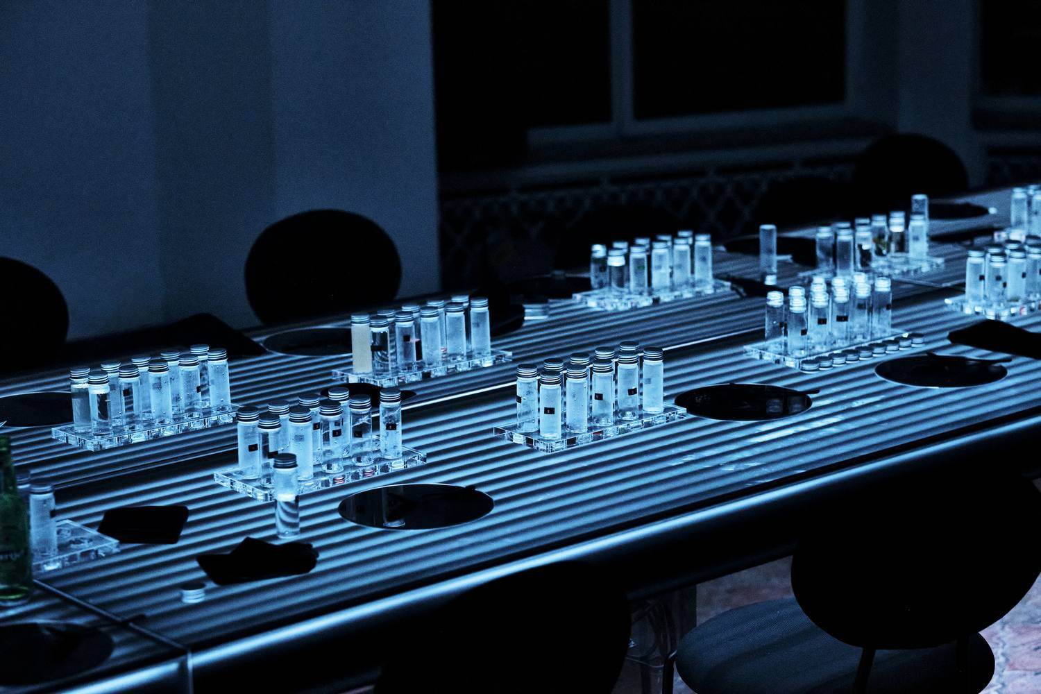 The Tabula Rasa table: a long acrylic table with light integrated into the surface, set with glass vials
